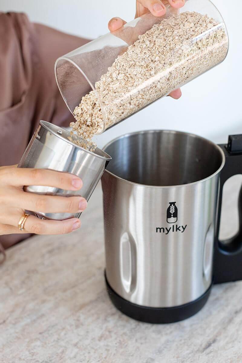 Pouring oats into a filter cup to make plant-based milk using a Mylky machine