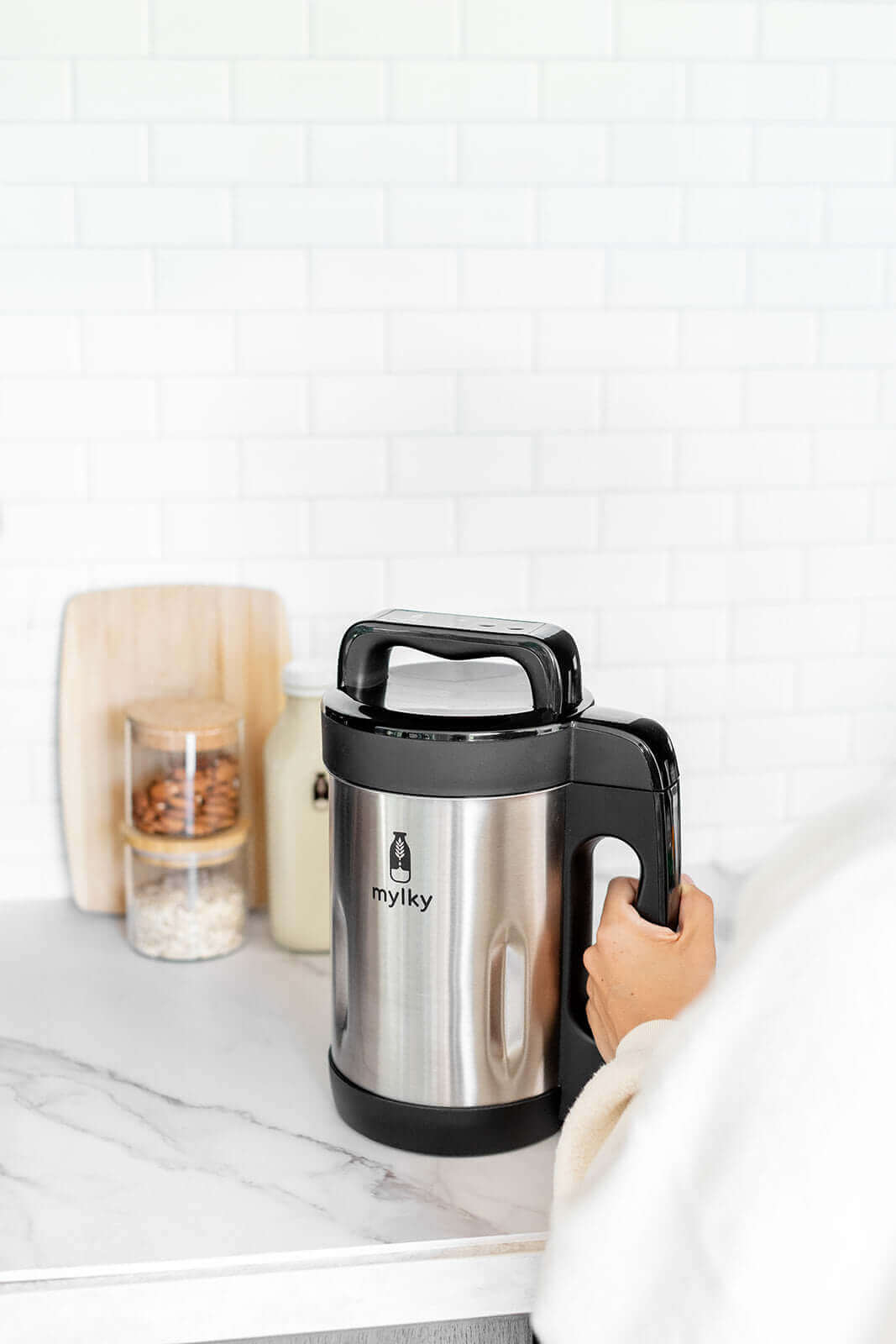 Person holding a Mylky plant-based milk maker on a kitchen counter